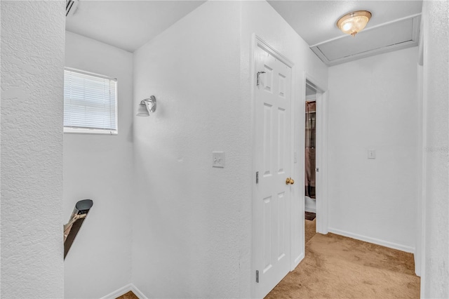 corridor with baseboards and light carpet