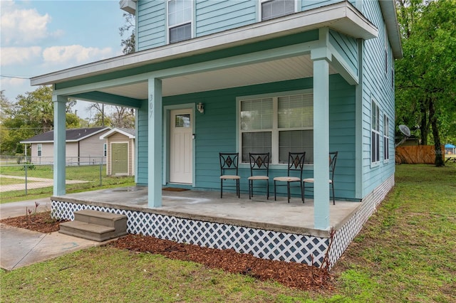 exterior space with a lawn, a porch, and fence