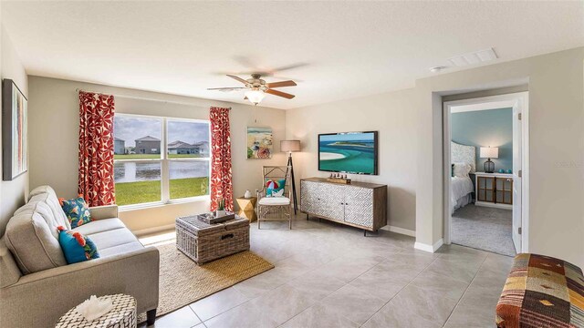 living area featuring light tile patterned floors, visible vents, baseboards, and a ceiling fan