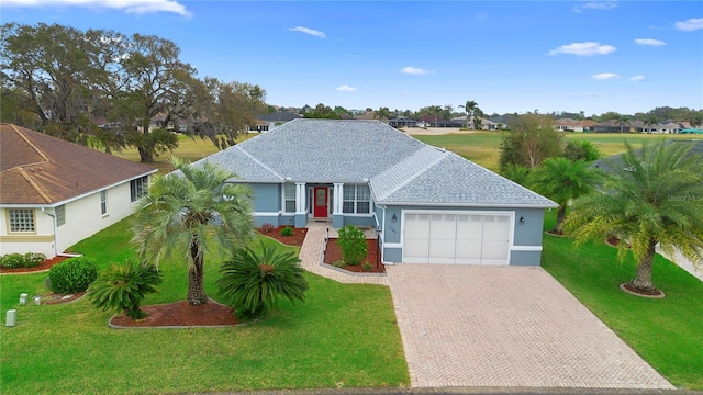 single story home featuring a garage, decorative driveway, a front yard, and a shingled roof