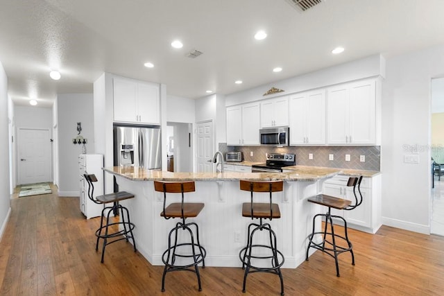 kitchen with decorative backsplash, light wood-type flooring, and appliances with stainless steel finishes