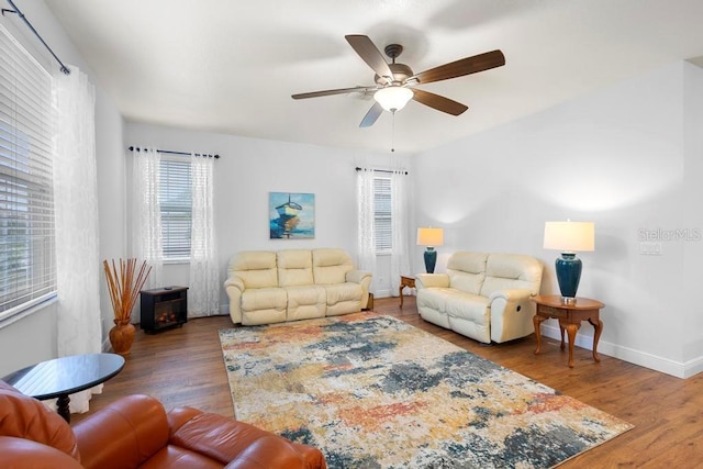 living area featuring a ceiling fan, baseboards, and wood finished floors