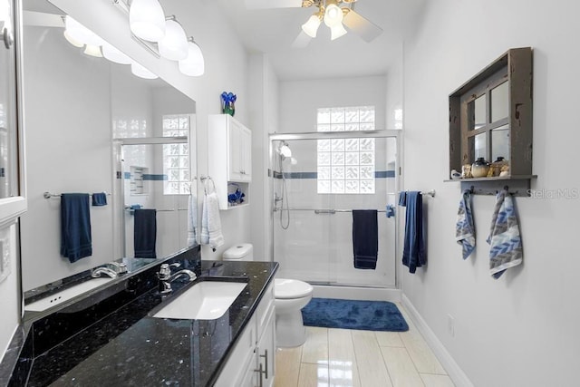 bathroom featuring vanity, a ceiling fan, baseboards, a shower stall, and toilet