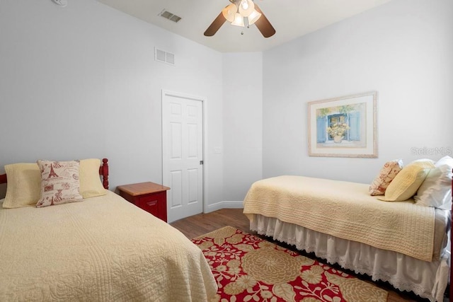 bedroom featuring visible vents, baseboards, a ceiling fan, and wood finished floors