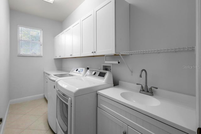 laundry area with light tile patterned floors, baseboards, cabinet space, a sink, and independent washer and dryer