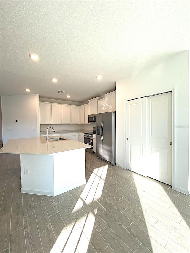 kitchen featuring a sink, white cabinetry, appliances with stainless steel finishes, light countertops, and wood tiled floor