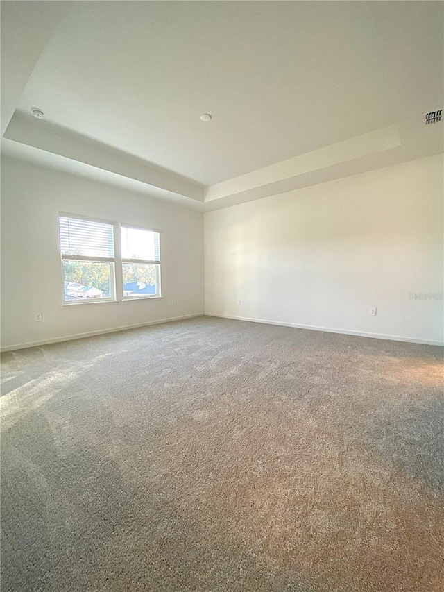 unfurnished room with visible vents, baseboards, a raised ceiling, and carpet