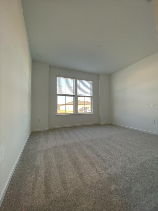 empty room featuring baseboards and light colored carpet