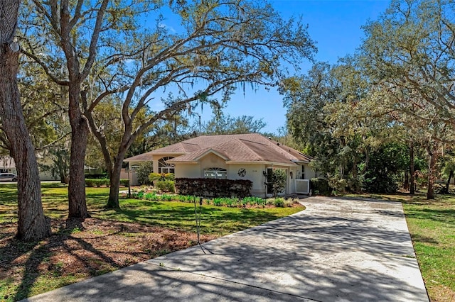 single story home with a front yard, driveway, and stucco siding