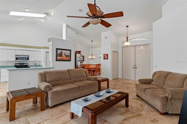 living room featuring a skylight, stone finish floor, ceiling fan with notable chandelier, and high vaulted ceiling