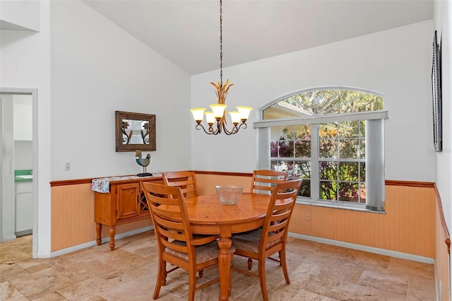 dining room with a wainscoted wall, wooden walls, and stone finish floor