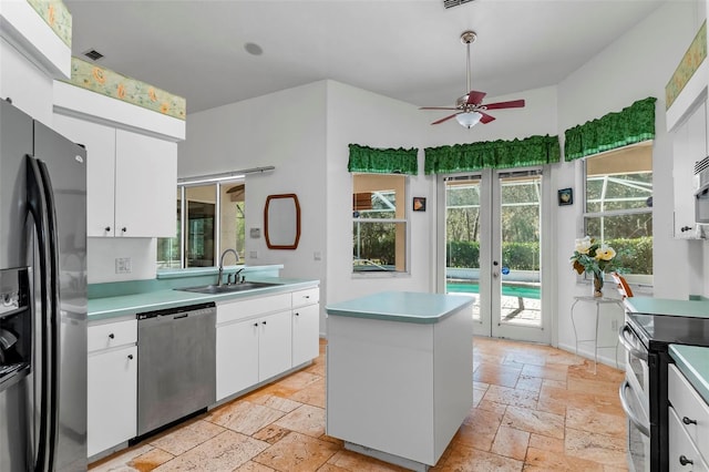 kitchen featuring a sink, stone tile floors, stainless steel appliances, white cabinets, and light countertops