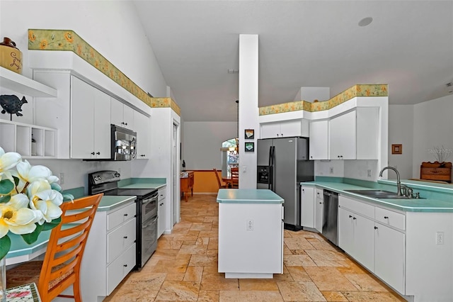 kitchen with a center island, stone tile floors, appliances with stainless steel finishes, white cabinetry, and a sink