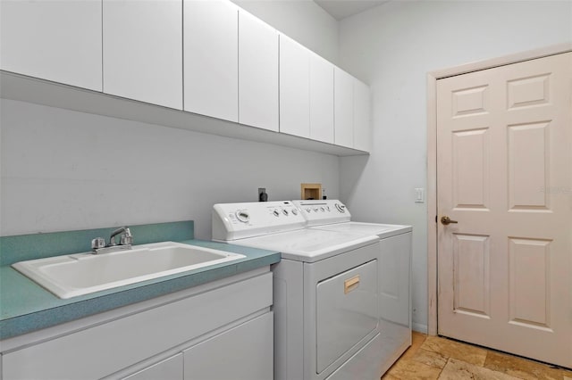 clothes washing area featuring a sink, cabinet space, separate washer and dryer, and stone tile floors