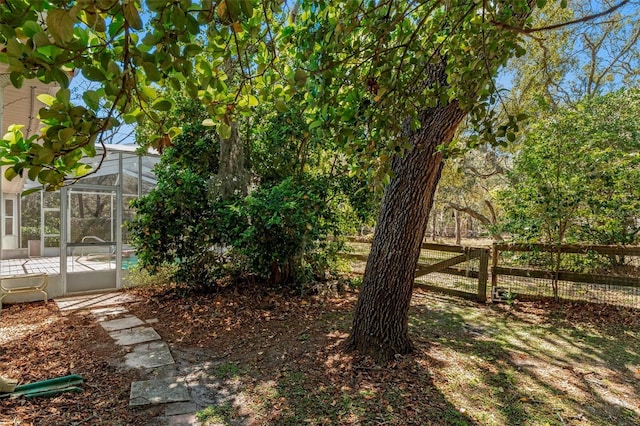 view of yard with glass enclosure and fence