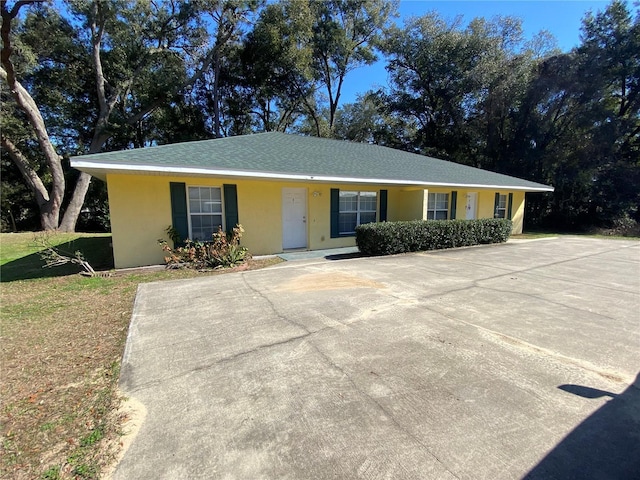 ranch-style home with stucco siding and a front lawn