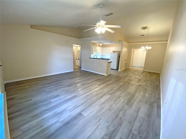 unfurnished living room with baseboards, visible vents, lofted ceiling, ceiling fan with notable chandelier, and light wood-type flooring