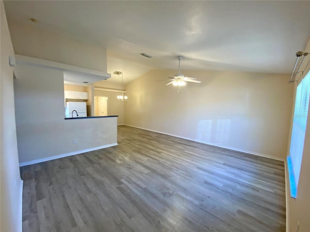 unfurnished living room featuring baseboards, lofted ceiling, ceiling fan with notable chandelier, dark wood-style floors, and a sink