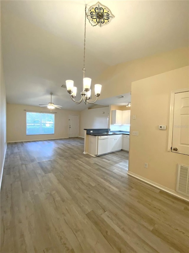 kitchen with visible vents, light wood finished floors, vaulted ceiling, dark countertops, and open floor plan