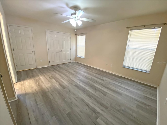 unfurnished bedroom with ceiling fan, a closet, baseboards, and wood finished floors