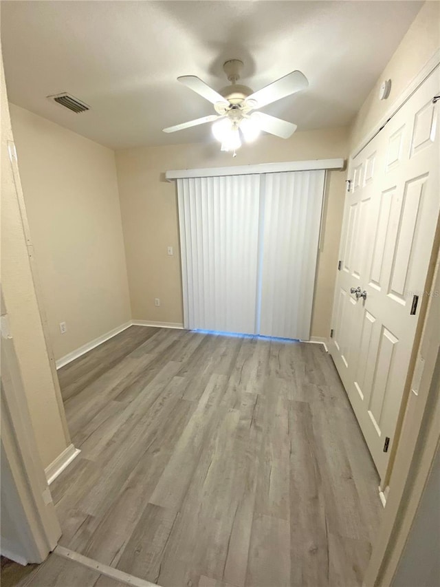 unfurnished bedroom with visible vents, baseboards, wood finished floors, and a ceiling fan