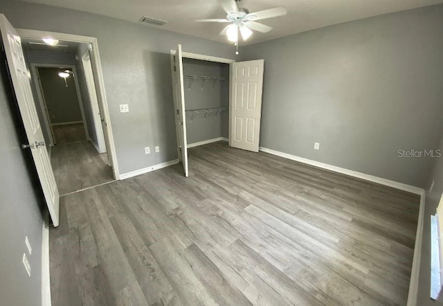 unfurnished bedroom with visible vents, baseboards, a closet, and wood finished floors