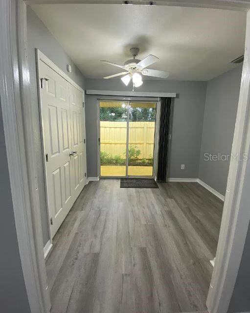 unfurnished bedroom with visible vents, access to outside, wood finished floors, baseboards, and ceiling fan