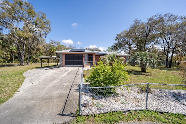 view of front of property with a fenced front yard, a carport, solar panels, and concrete driveway