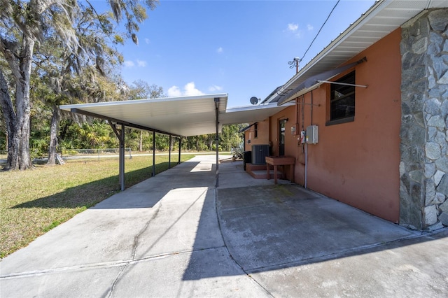 view of patio / terrace with an attached carport, concrete driveway, central AC, and fence