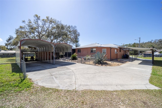 exterior space with metal roof, a detached carport, concrete driveway, and fence