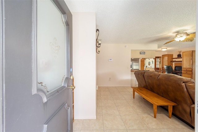 interior space featuring light tile patterned floors, baseboards, a textured ceiling, and a ceiling fan