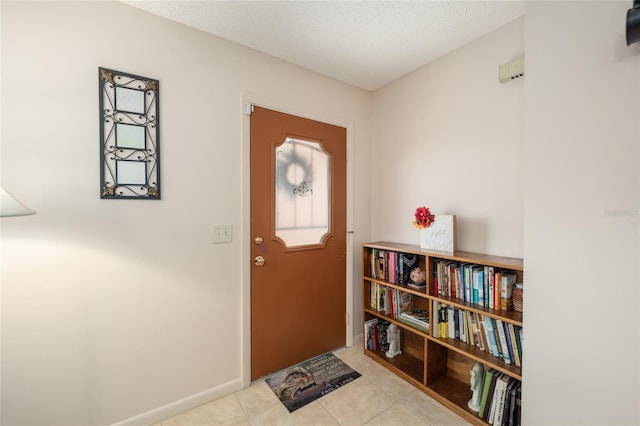 tiled foyer entrance featuring baseboards and a textured ceiling