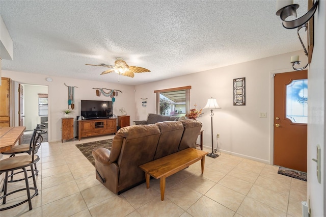 living room with light tile patterned flooring, a ceiling fan, baseboards, and a textured ceiling