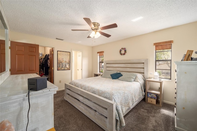 carpeted bedroom featuring visible vents, ceiling fan, a closet, a textured ceiling, and a walk in closet