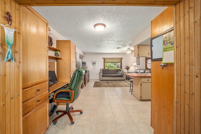 office with ceiling fan, light tile patterned floors, built in desk, and a textured ceiling