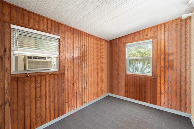 empty room with cooling unit, baseboards, and wooden walls