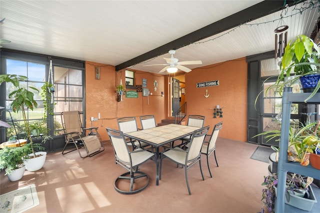 sunroom featuring beamed ceiling and a ceiling fan