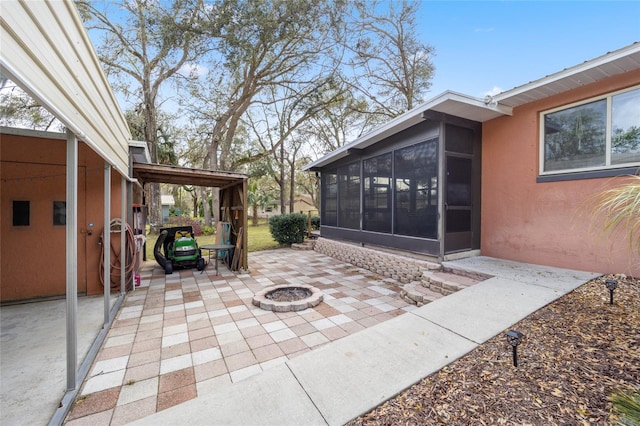 view of patio with an outdoor fire pit and a sunroom