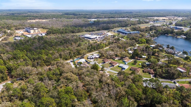 drone / aerial view with a wooded view and a water view