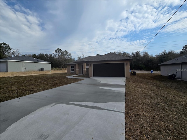 view of front facade featuring an attached garage, central AC, and driveway