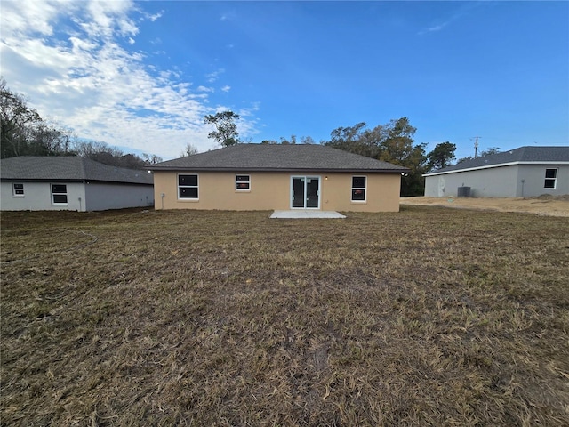 back of house with a patio, a lawn, and stucco siding