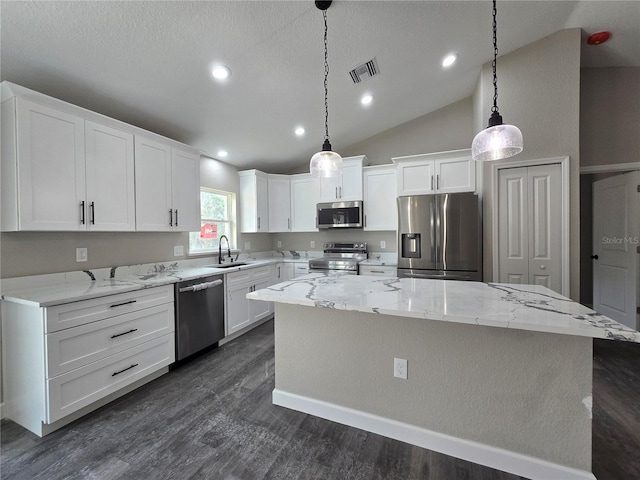 kitchen featuring visible vents, a sink, stainless steel appliances, white cabinetry, and a center island