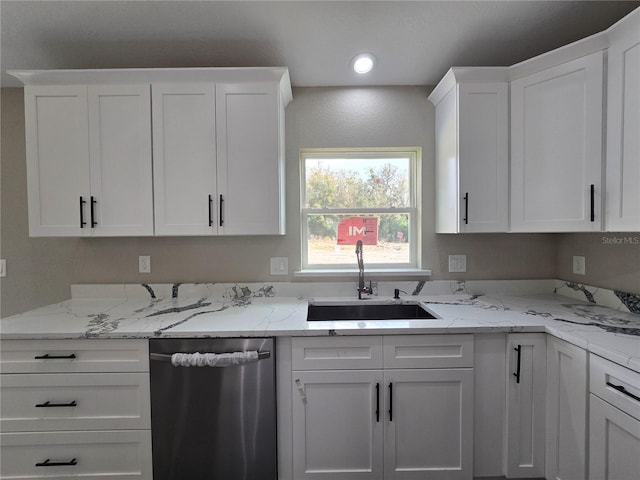 kitchen featuring dishwasher, light stone countertops, white cabinetry, and a sink