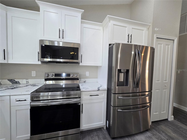 kitchen featuring white cabinets, appliances with stainless steel finishes, dark wood-type flooring, and light stone countertops