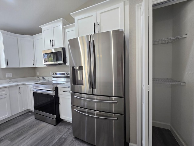 kitchen with baseboards, dark wood finished floors, light countertops, appliances with stainless steel finishes, and white cabinetry