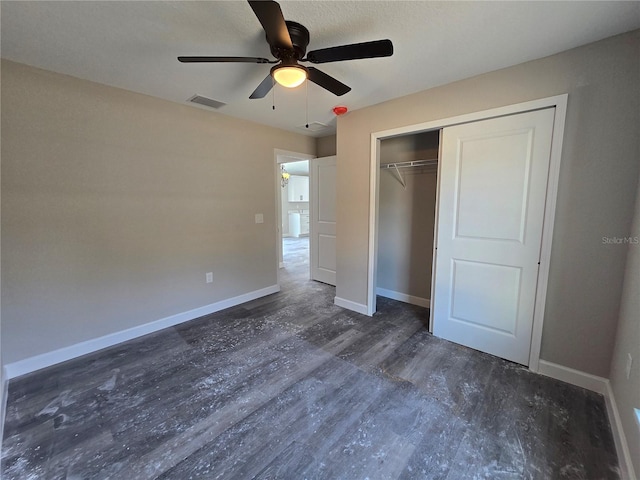 unfurnished bedroom with a ceiling fan, visible vents, wood finished floors, baseboards, and a closet