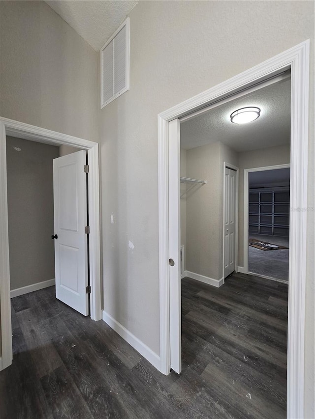 hallway featuring a textured ceiling, baseboards, and wood finished floors