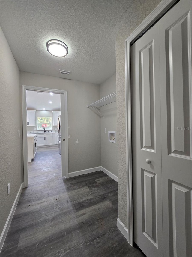 washroom with visible vents, washer hookup, dark wood-style floors, baseboards, and a textured wall