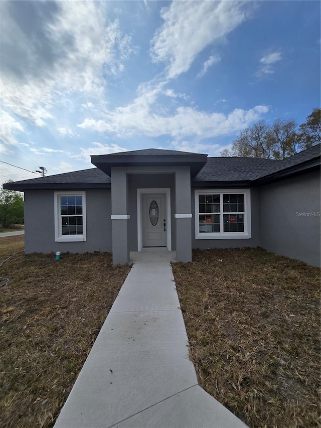 view of front of property with stucco siding and roof with shingles