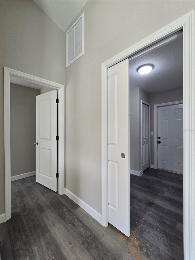 hallway with visible vents, baseboards, and dark wood-style floors